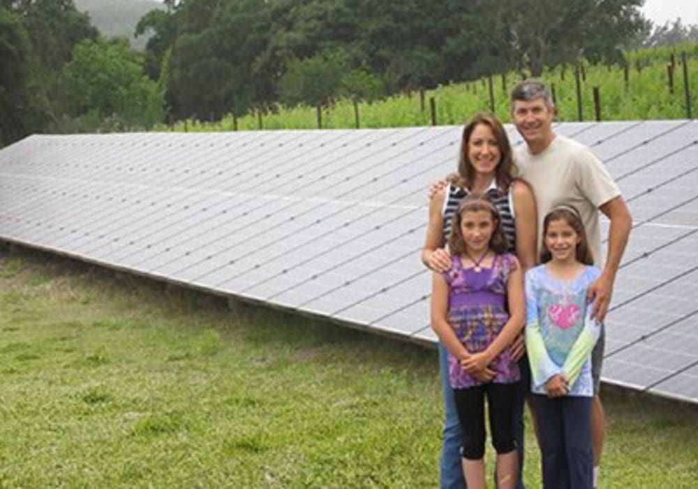 family standing in front of solar panels on grass