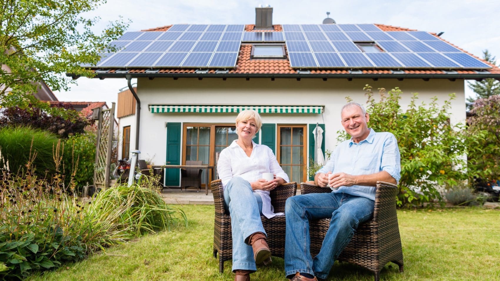 older couple sitting in backyard with solar panels on roof